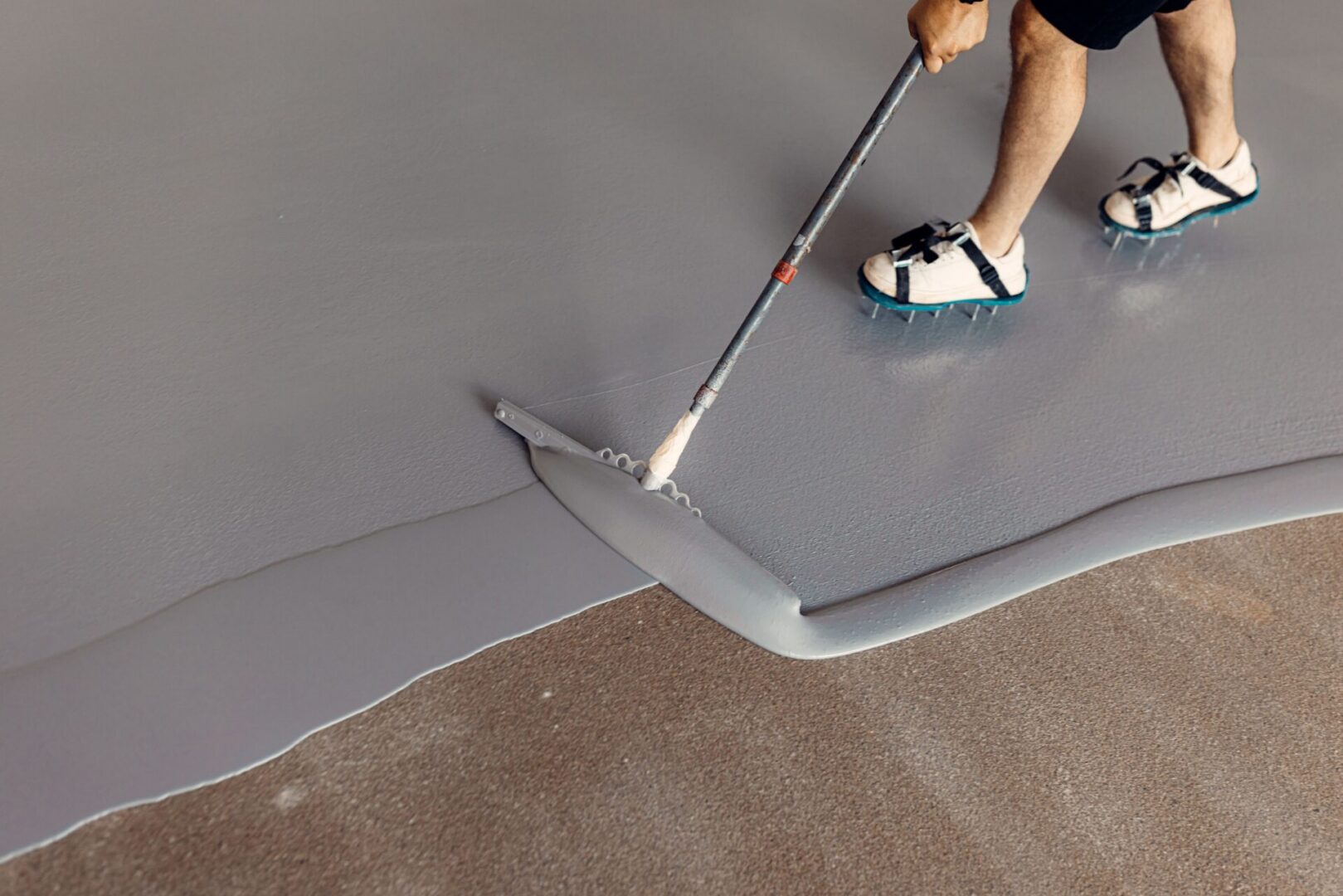 Person spreading gray floor coating.